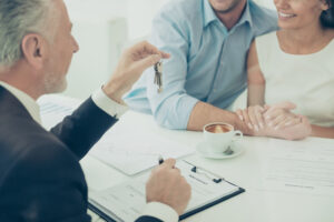 Close up of real estate agent giving keys to couple of customers