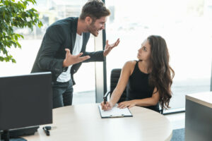 strict boss man swearing at employee woman for bad work at the workplace looking angry